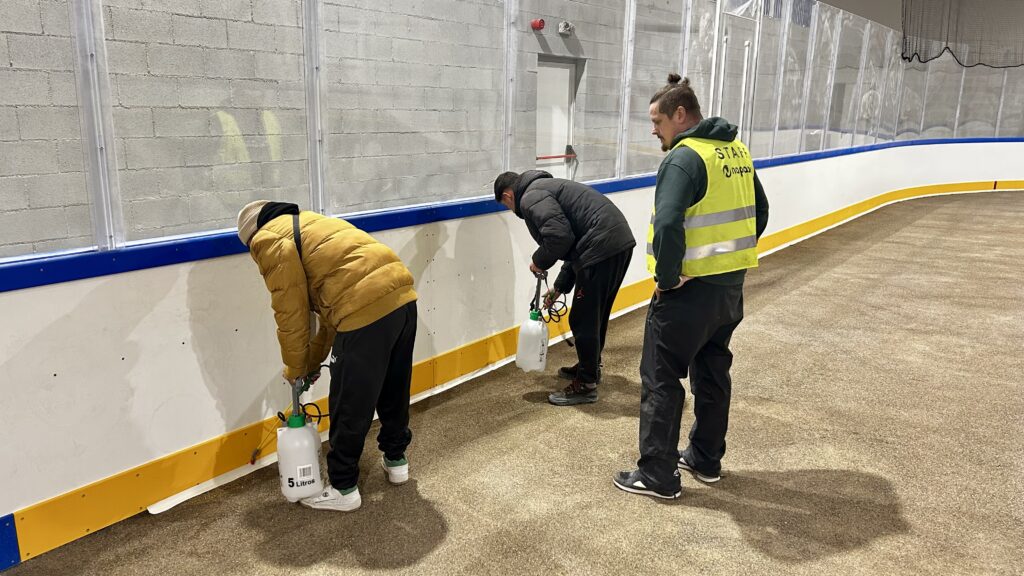 Tecnicos realizando el mantenimiento de las barreras perimetrales y los bordes de la pista de hielo