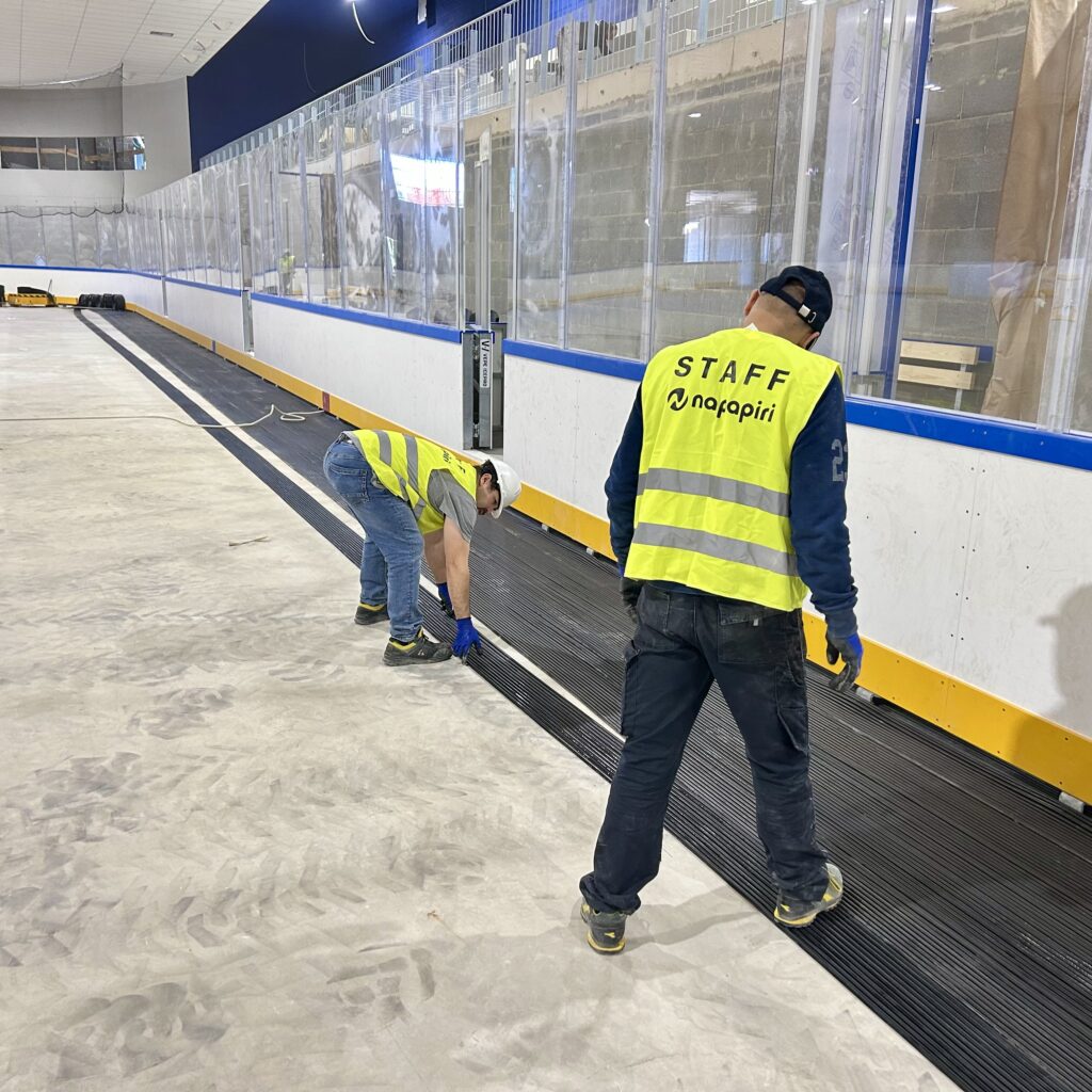 Personal de NAPAPIRI instalando un nuevo suelo de hielo EPDM durante la renovacion de una pista