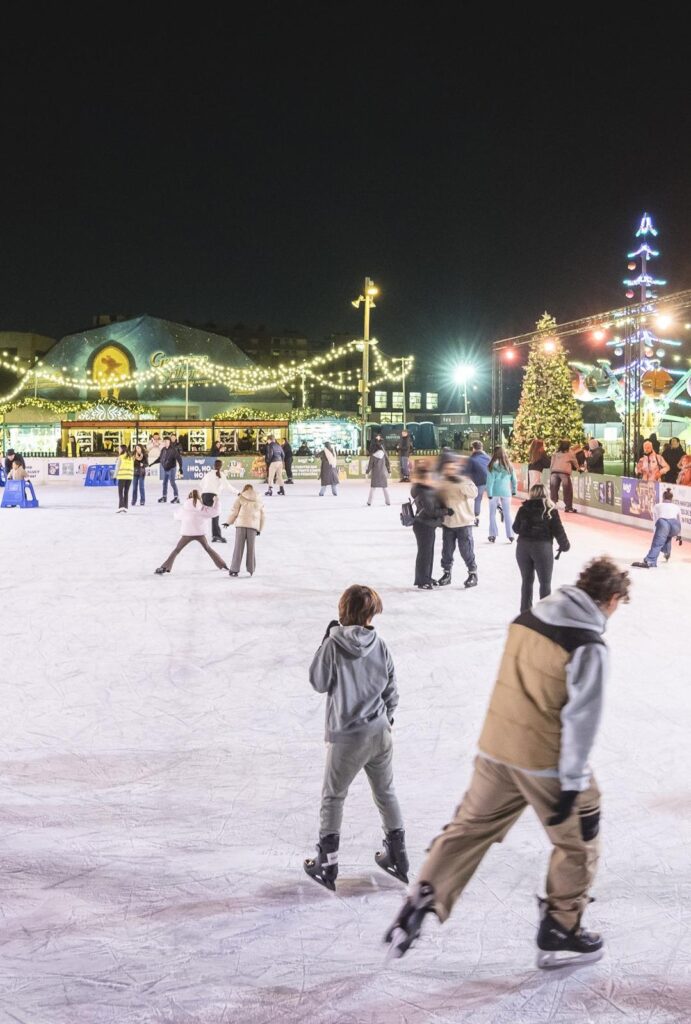 Visitantes patinando en una concurrida pista de hielo publica con patines de alquiler profesionales